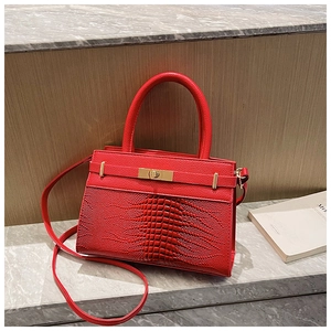 Detail of red crocodile texture leather handbag featuring a gold metallic twist lock