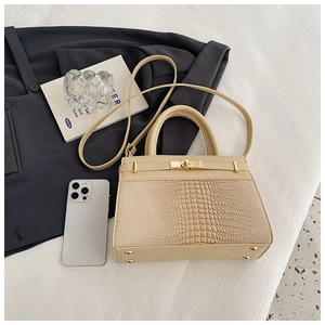 Detailed macro view of beige crocodile textured faux leather handbag with gold metal lock