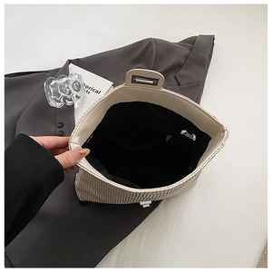 Detail of cream corduroy shoulder bag showing interior lining and zippered inner pocket
