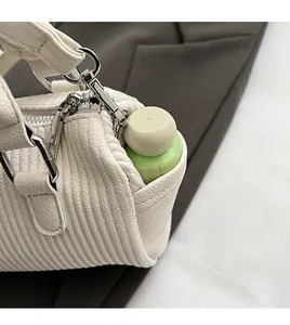 Detail view of the side pocket of a cream handbag showing storage for a water bottle