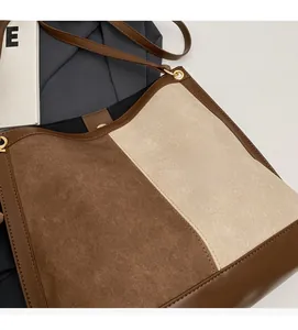 Detail of contrast stitching, suede texture, and leather strap on a large bucket bag