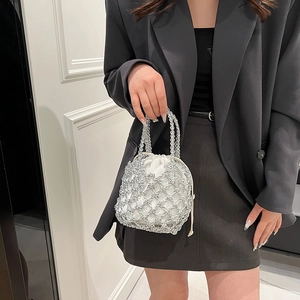 Detail of silver woven metal mesh bucket bag with a white satin drawstring pouch