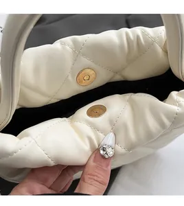 Macro shot of high-quality gold magnetic buckle on off-white quilted bucket bag
