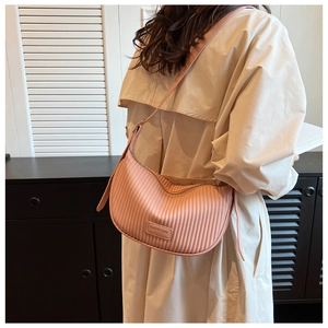 Close-up of pink pleated cloud bag with vertical texture and sleek shoulder strap
