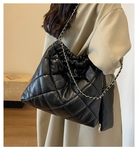 Detail of black quilted tote bag with gold chain strap and mini side pouch