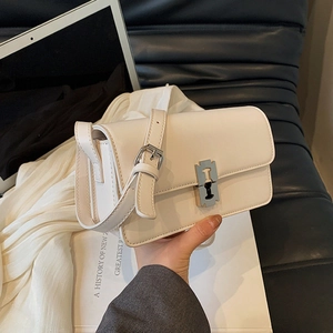 Minimalist beige leather saddle bag with distinctive metal buckle and adjustable strap