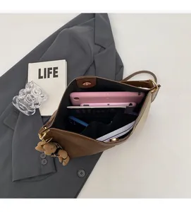 Top view of spacious brown bucket bag interior holding a tablet and daily essentials