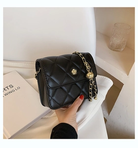 Close-up of quilted chain bag featuring a golden camellia flower clasp and metal chain