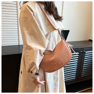 Detail of soft pink pleated leather shoulder bag with fine vertical texture and metal zipper