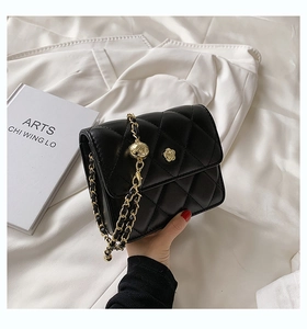 Detail of black quilted crossbody bag with floral buckle and golden chain strap