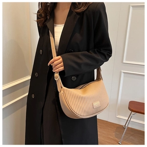 Detail of beige pleated crescent bag with adjustable strap and metallic hardware