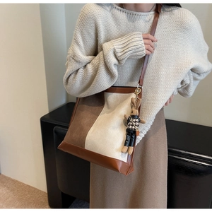 Detail view of large color-block bucket bag with a cute rabbit charm on a model