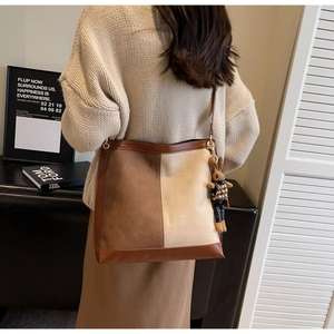 Detailed close-up of the two-tone bucket bag with cute rabbit pendant and metal buckle