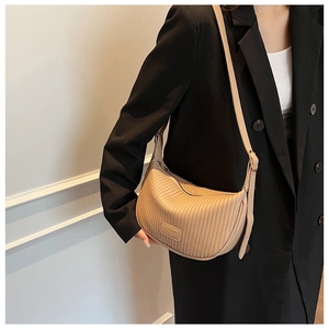 Close-up of beige pleated crescent bag showing vertical textures and adjustable strap
