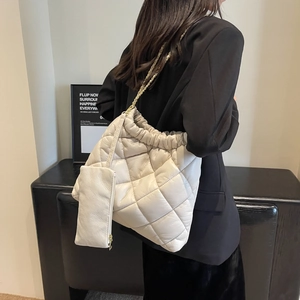Close-up of quilted white tote bag with gold chain and matching mini pouch accessory