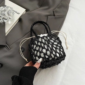 Detail of black hollow woven bag with white drawstring liner and tassel accents