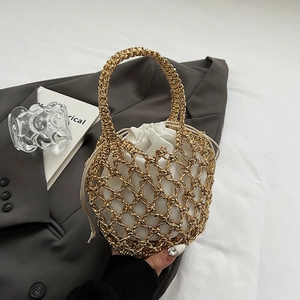Detailed view of hollow gold metal mesh handbag with a white drawstring liner on a grey blazer