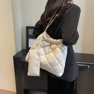 Close-up of beige quilted tote bag with gold chain strap and mini purse accessory