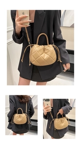 Detail view of beige quilted cloud bucket bag with drawstring closure and slim shoulder strap