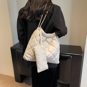 Detail of cream quilted tote bag with gold chain strap and detachable pouch