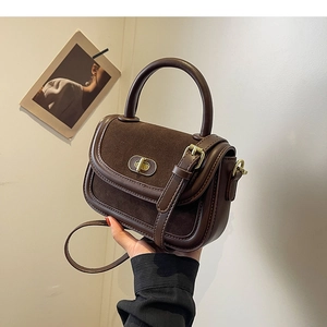 Sac bandoulière vintage en cuir marron avec boucle dorée et finitions texturées