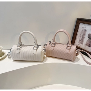 Detail of pleated mini boston bags in pearl white and pink with adjustable straps