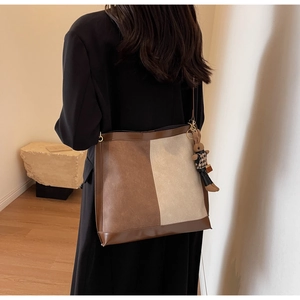 Detail of a large brown and beige color-block tote bag with a cute rabbit charm