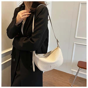Detail of cream pleated crossbody bag featuring wavy texture and adjustable strap