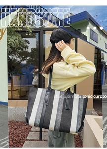 Detail of vertical striped tote bag with black leather handles in an outdoor setting