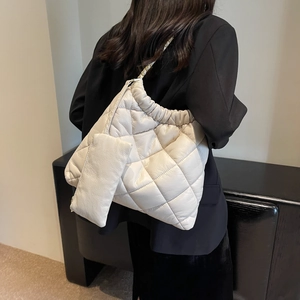 Close-up of quilted cream tote bag with woven chain strap and matching mini pouch accessory