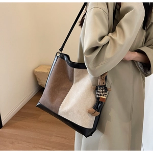 Detail of color-block tote bag with a cute rabbit charm shown on a trench coat model