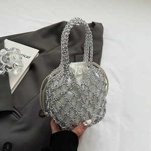 Detail of silver hollow metal mesh bag featuring a white drawstring inner pouch and tassel