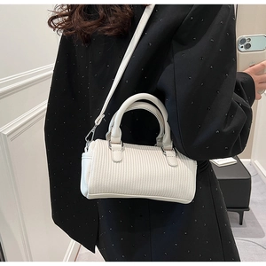 Detail of white striped embossed leather handbag with metal hooks and slim shoulder strap