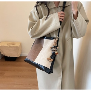 Detail of color-block bucket bag in brown and cream with a cute rabbit charm