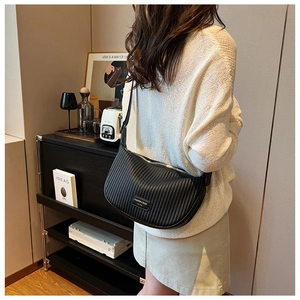 Detail of black pleated dumpling bag showing textured vertical folds and leather strap
