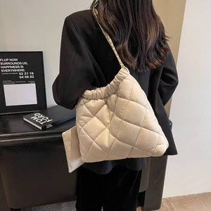 Detail of oversized quilted tote bag with drawstring closure and chain strap