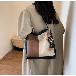 Close-up of color-block tote bag with a cute brown rabbit charm on the side strap