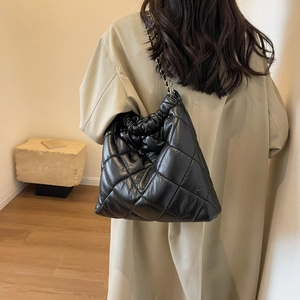Detailed view of black quilted faux leather tote with elegant chain shoulder strap