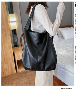 Close-up of black PU leather tote bag with lychee texture shown on a female shoulder