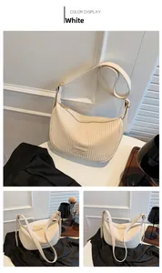 Detailed view of white pleated dumpling bag featuring golden zipper and adjustable strap