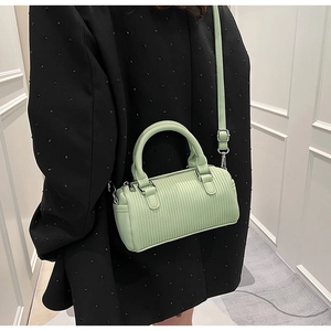 Detail of light green pleated barrel bag with silver hardware and adjustable strap