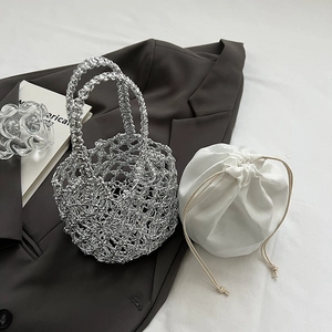 Detail of silver woven crochet bag with white drawstring liner on a brown blazer background