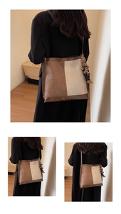 Detail of a large brown and beige color-block bucket bag with a plush bear charm