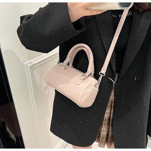 Pink pleated barrel handbag with silver hardware shown in a stylish crossbody wear