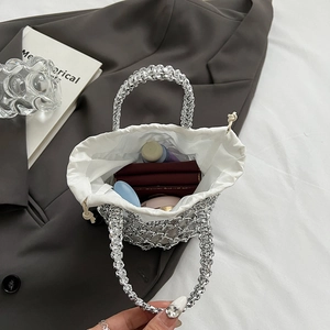 Silver woven hollow handbag detail showing interior pouch with lipstick and cosmetics