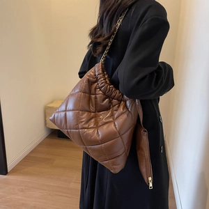 Detail of a brown quilted puffer tote bag with gold chain strap and mini side pouch