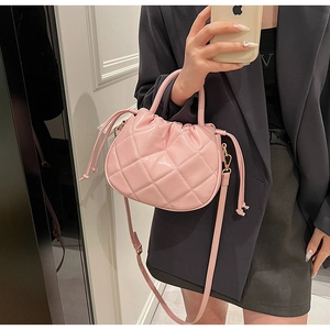 Close-up of pink quilted PU crossbody bag with drawstring detail and gold hardware