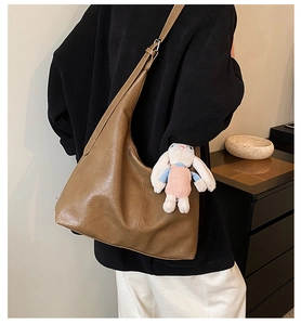 Detail view of large brown shoulder tote bag with cute plush rabbit charm on side