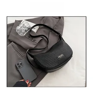 Detailed texture of black pleated hobo bag styled with office blazer and accessories