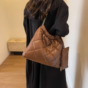 Close-up of brown quilted diamond pattern tote bag with metal chain and coin purse